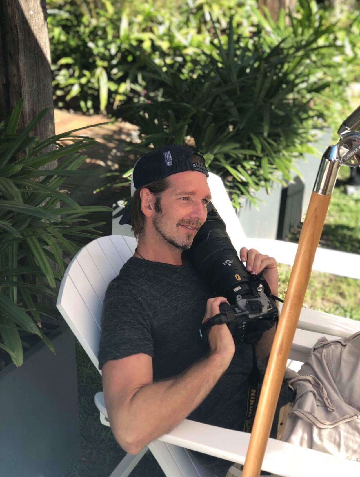 Dave Blake relaxing on location with a camera in his hands, surrounded by greenery
