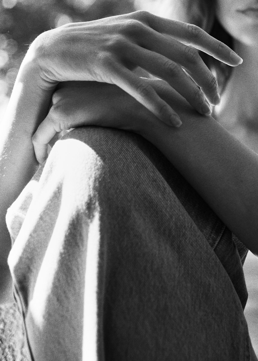 Black-and-white detail of Jess Holiday's hands resting on her knee