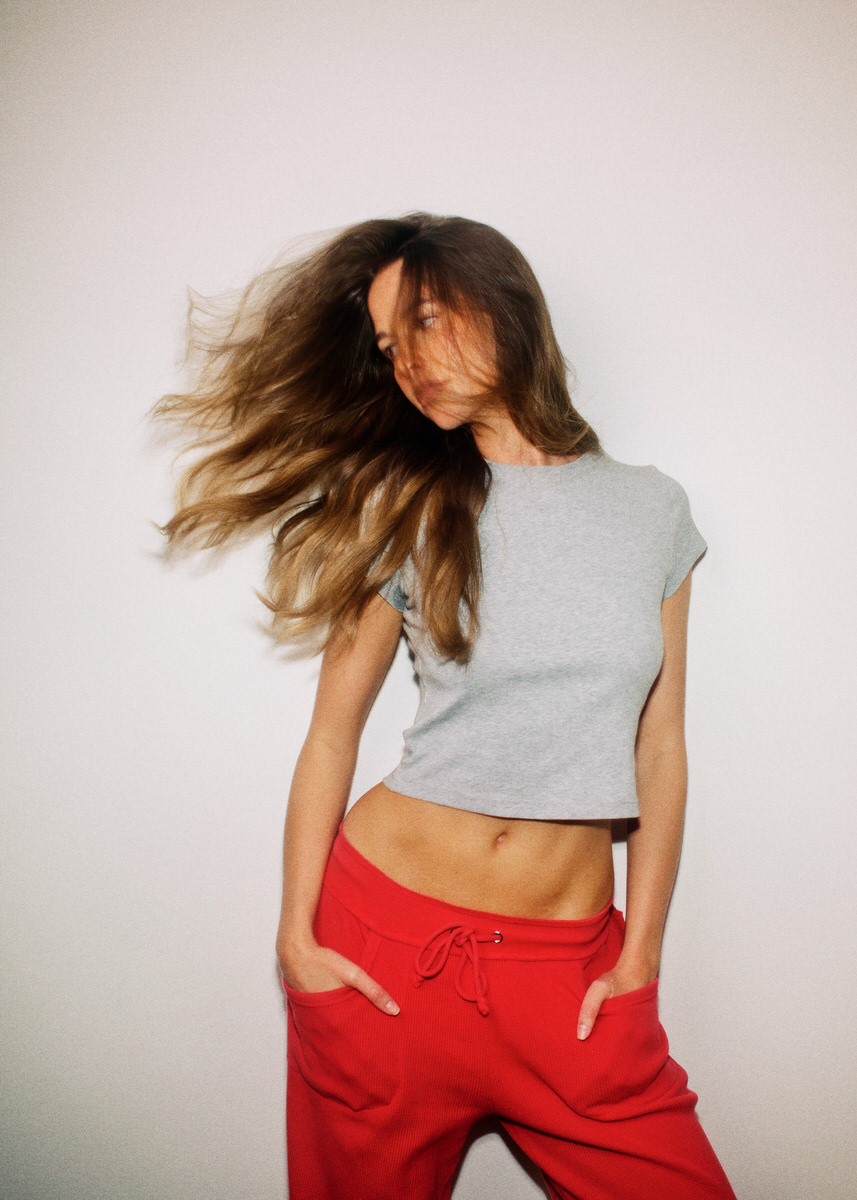 Jess Holiday moving in a grey cropped top and red trousers