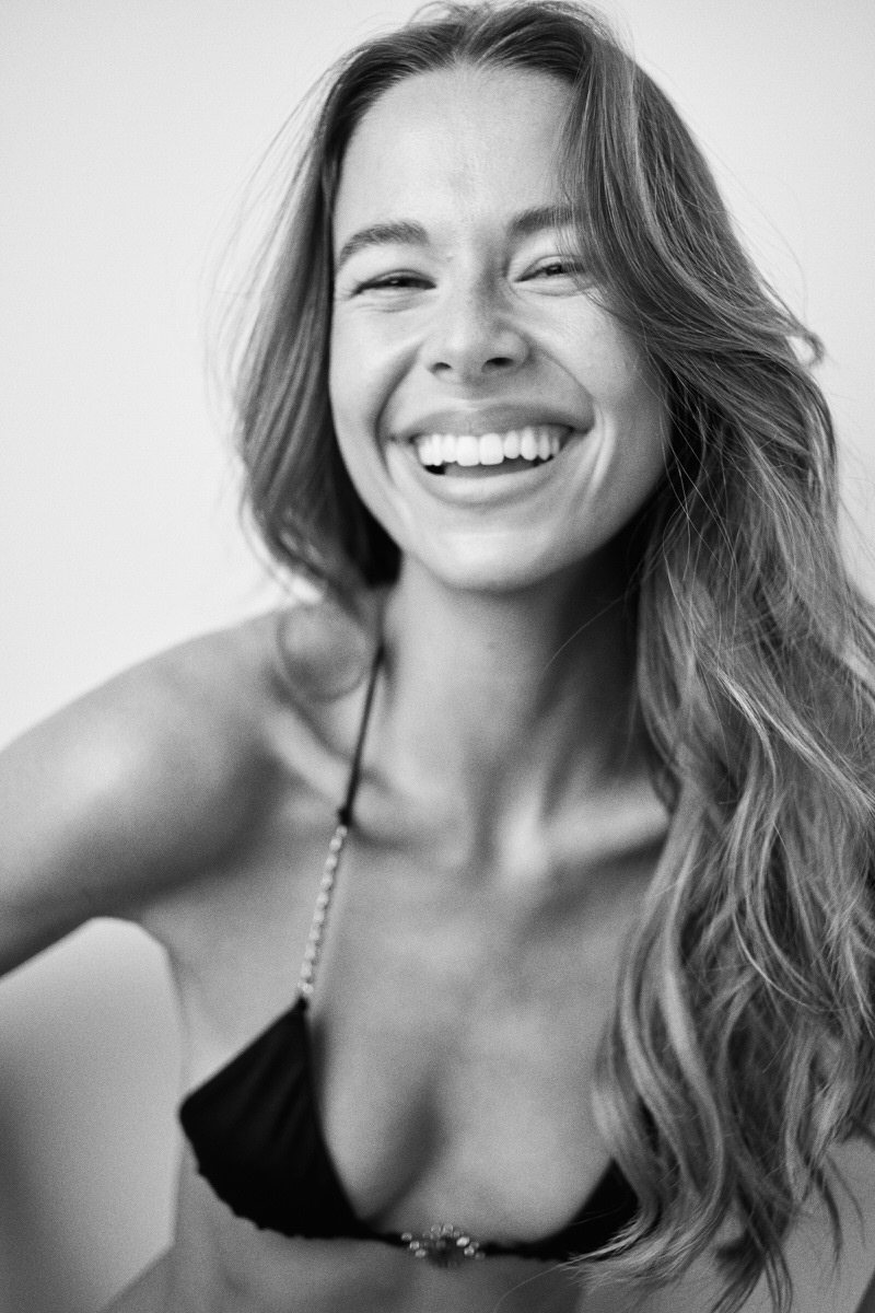 Black-and-white portrait of Jess Holiday laughing in black swimwear