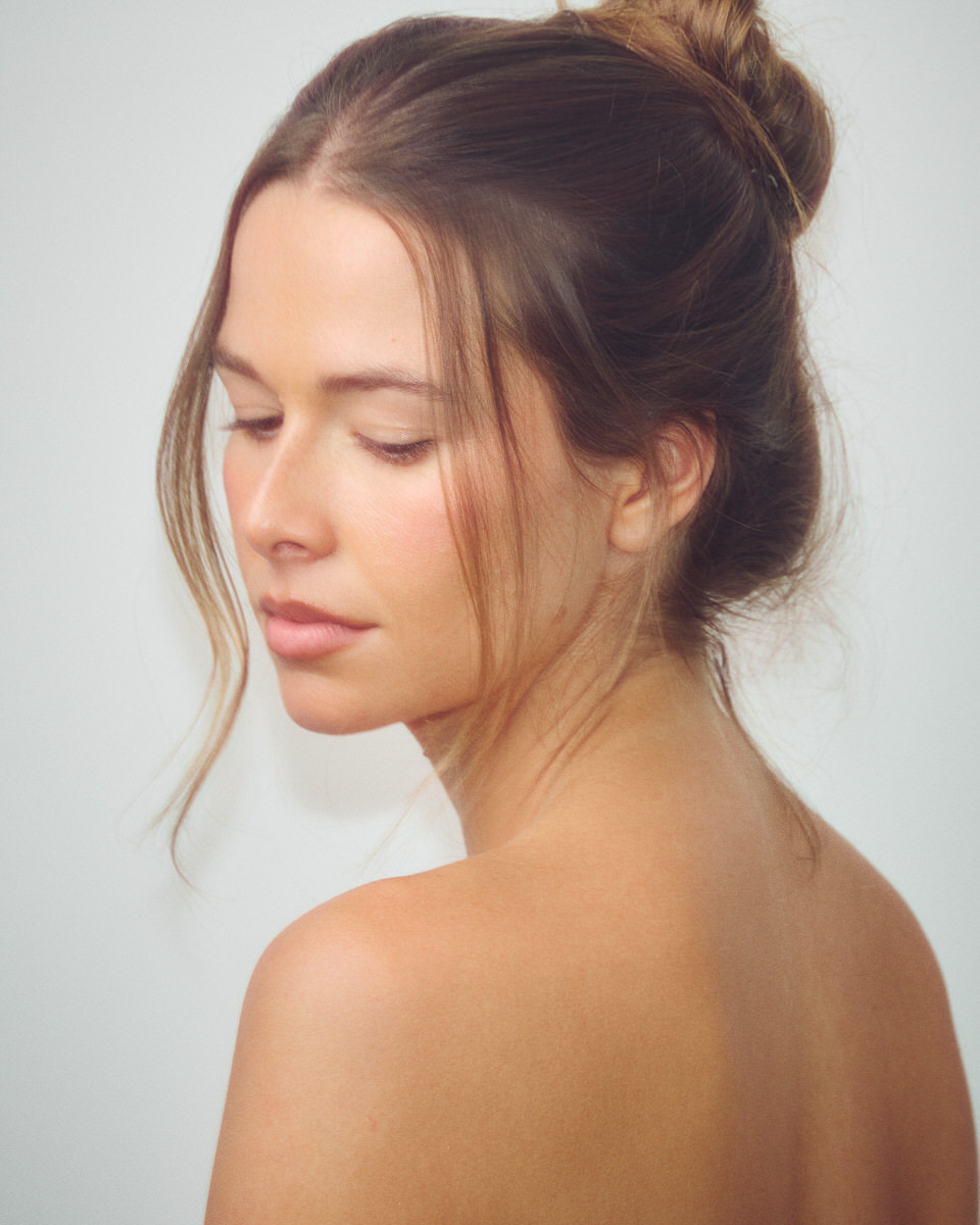 Colour portrait of Jess Holiday looking down over her shoulder with her hair in a loose bun