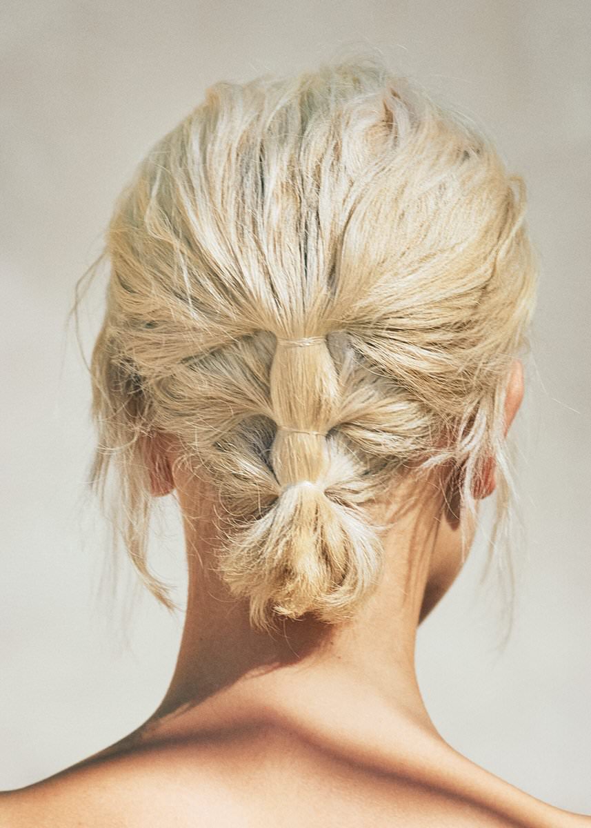 Blonde hair arranged in a textured low updo, photographed from behind for R+Co Bleu
