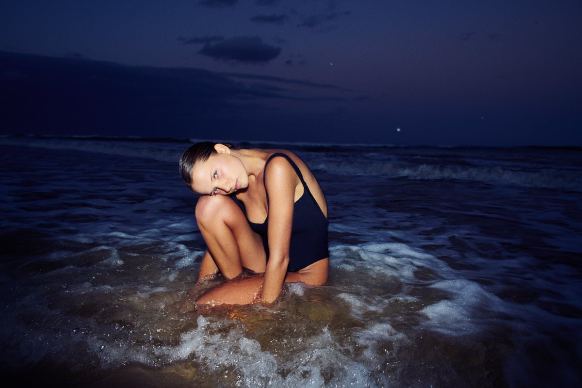 Camilla Muller in a black swimsuit in the ocean at blue hour